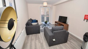 A modern living room with a sofa set, a television, and a lamp. - Bright & Spacious 2 Bed Apartment in Manchester (Manchester)