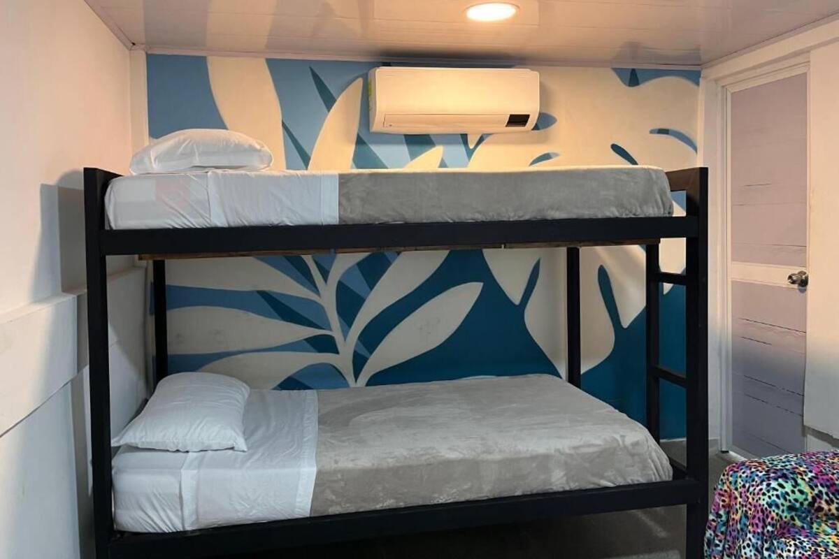 A bunk bed with a wall-mounted air conditioner above it.