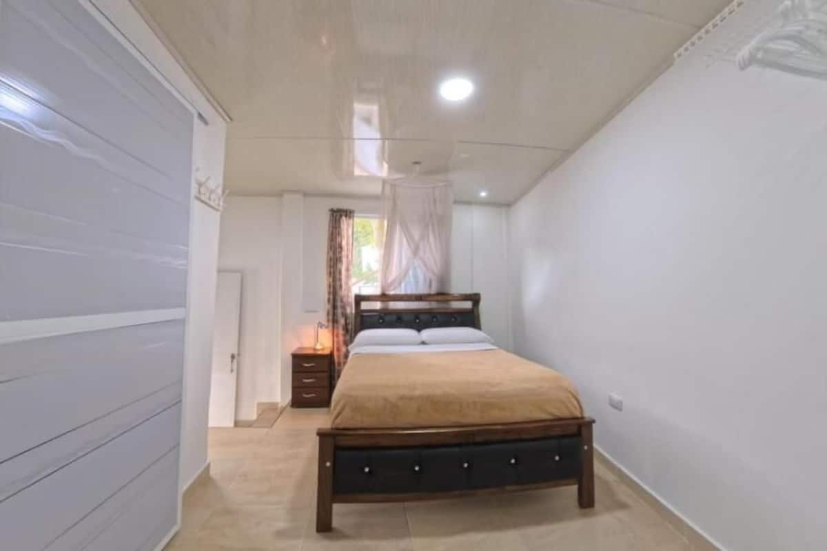 A bedroom with a bed, bedside table, and a window with curtains.