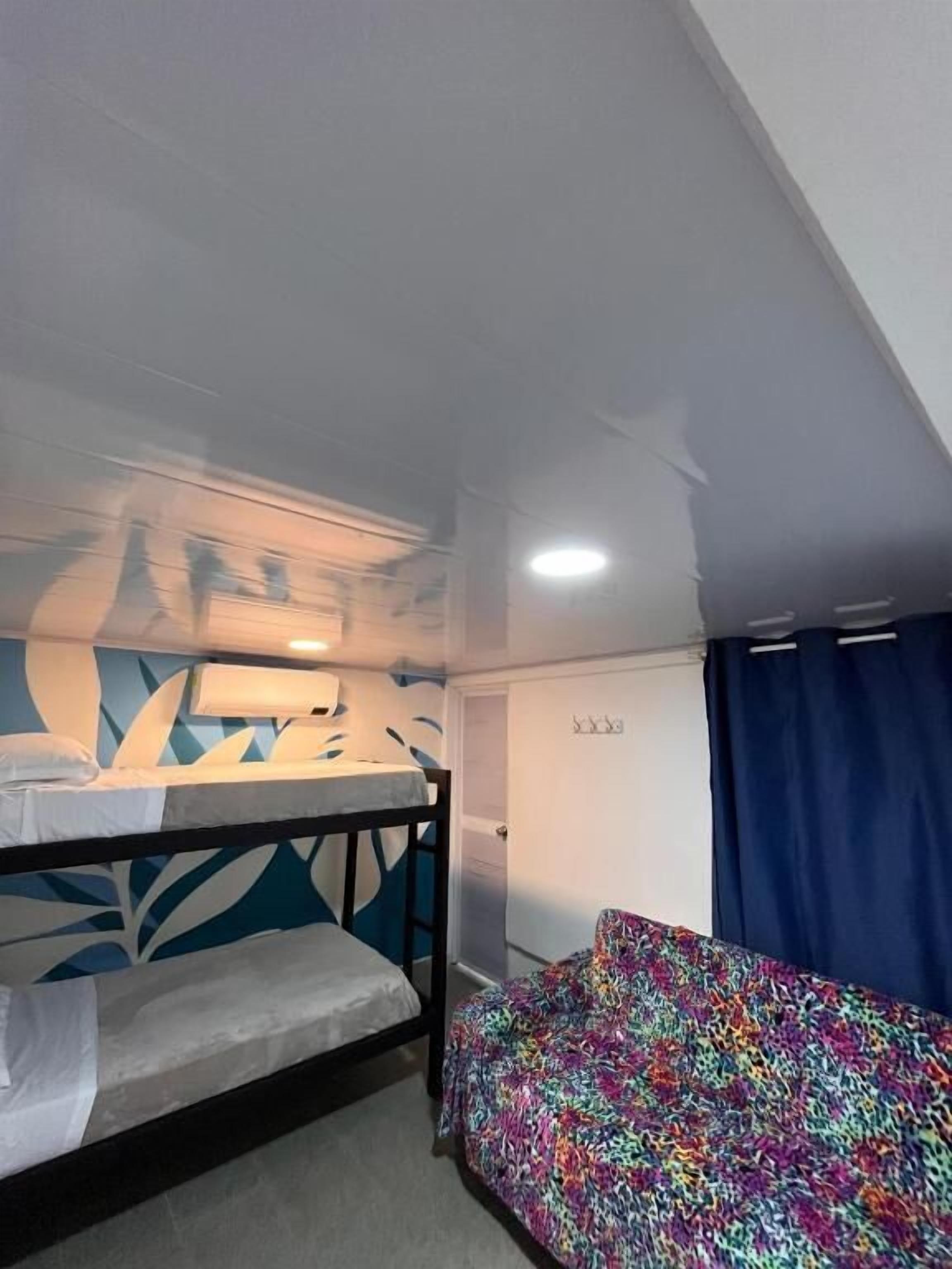 Une pièce avec des lits superposés, un mur décoré de motifs, une porte et une fenêtre avec des rideaux.