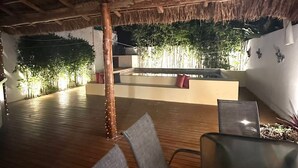 Un vaste espace intérieur doté d’un plancher en bois, d’un toit de chaume et d’un coin salon avec des chaises.