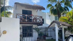 Une maison à deux étages avec un balcon, une cour clôturée et une voiture garée devant.