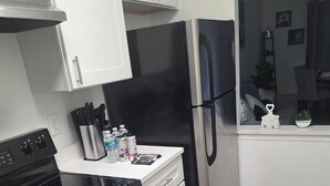 Una cucina moderna con mobili bianchi, un frigorifero nero, elettrodomestici in acciaio inossidabile e un pavimento in legno.