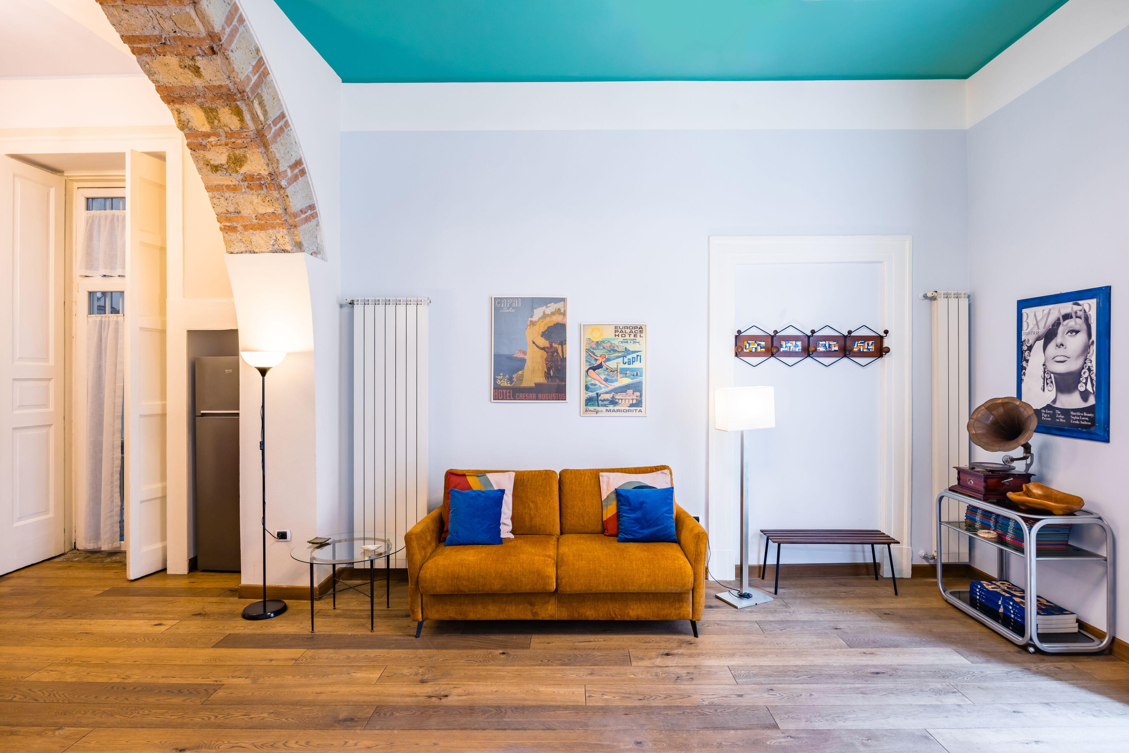 A living room with a sofa, a coffee table, a lamp, a radiator, and a bookshelf.