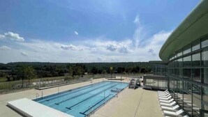 A swimming pool with a clear view of the surrounding landscape and a modern building with large windows. - Charming stone house in the heart of the Vexin, enclosed garden and view of the bell tower (Vaudancourt)