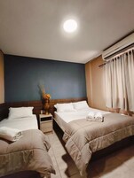 Habitación de hotel con dos camas, una mesita de noche, un jarrón con flores y un equipo de aire acondicionado.