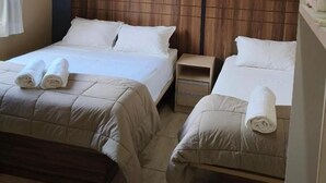 A hotel room with two beds, a ceiling fan, a nightstand, and a window with curtains. - Hotel Cardinal Pedro Juan Caballero (Pedro Juan Caballero)