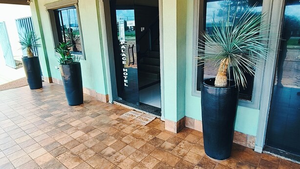 A hotel entrance with tiled flooring, potted plants, and a wooden ceiling. - Hotel Cardinal Pedro Juan Caballero (Pedro Juan Caballero)