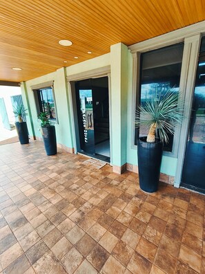 A hotel entrance with tiled flooring, potted plants, and a wooden ceiling. - Hotel Cardinal Pedro Juan Caballero (Pedro Juan Caballero)