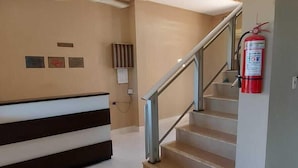 A reception area with a reception desk, a staircase, and a fire extinguisher. - Hotel Cardinal Pedro Juan Caballero (Pedro Juan Caballero)