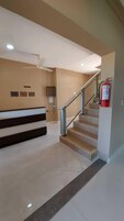 Zona de recepción con mostrador, escalera y extintor.