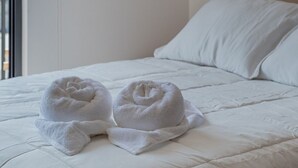 Une chambre d’hôtel avec un lit, deux étagères fixées au mur ornées de petites plantes, et une vue par la fenêtre.