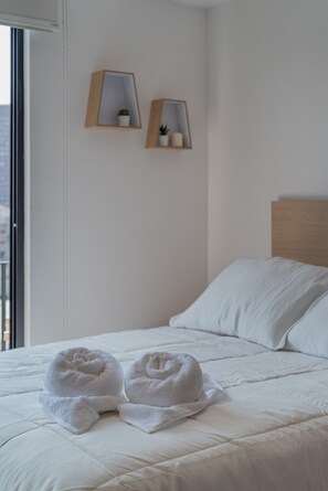 A hotel room with a bed, two wall-mounted shelves with small plants, and a view through a window. - Bright Loft by Reforma with Monument Views (Mexico City)