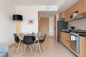 A modern kitchen with wooden cabinets, a stainless steel stove, and a microwave. - Bright Loft by Reforma with Monument Views (Mexico City)