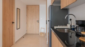 Une cuisine moderne dotée d’un plan de travail noir, d’un évier en acier inoxydable et d’une machine à café.