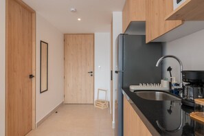 A modern kitchen with a black countertop, stainless steel sink, and a coffee machine. - Bright Loft by Reforma with Monument Views (Mexico City)