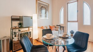 Un salon moderne avec une table à manger en verre, des chaises noires, un canapé et un téléviseur.