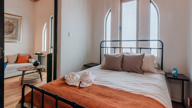 Une chambre à coucher avec un lit, une table de chevet, une fenêtre et une porte.
