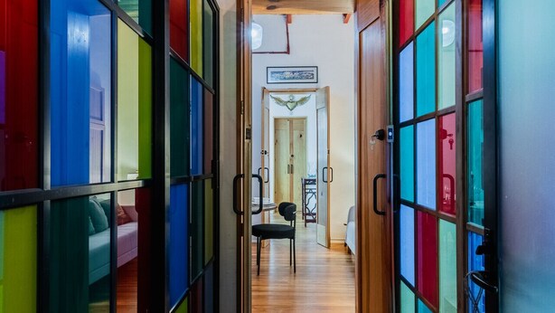 A hallway with colorful glass doors leading to a room with a bed and a table. - Stylish Roma Norte Loft | Walk to Cafés & Dining (Mexico City)