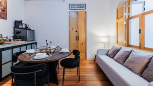 A dining area with a round table set for four, a sofa, and a kitchen area with a refrigerator and coffee machine. - Stylish Roma Norte Loft | Walk to Cafés & Dining (Mexico City)