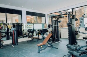 A gym with various exercise equipment, large windows, and a bench. - Modern 1BR| Heated Pool, Gym, Fast Wifi| Kileleshwa (Nairobi)