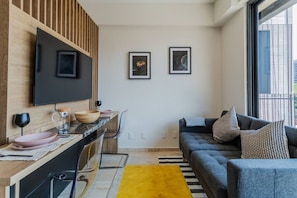 A modern living space with a kitchen area, a sofa, and a dining table. - Luxury loft with balcony in prime Roma Norte (Mexico City)