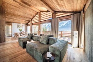 Ein Holzinnenraum mit einer Eckcouch, einem Essbereich und Blick auf Berge.