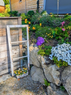 Ein Garten mit einer hölzernen Bank, einer rustikalen Glasdoor und einer Vielfalt bunter Blumen.