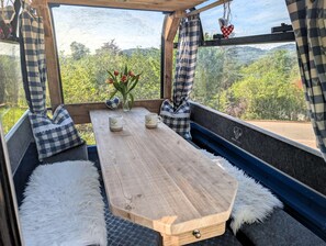 A cozy seating area with a wooden table, checkered cushions, and a vase with flowers. - VroniChalets - Tiny Chalet with sauna (Neukirchen)
