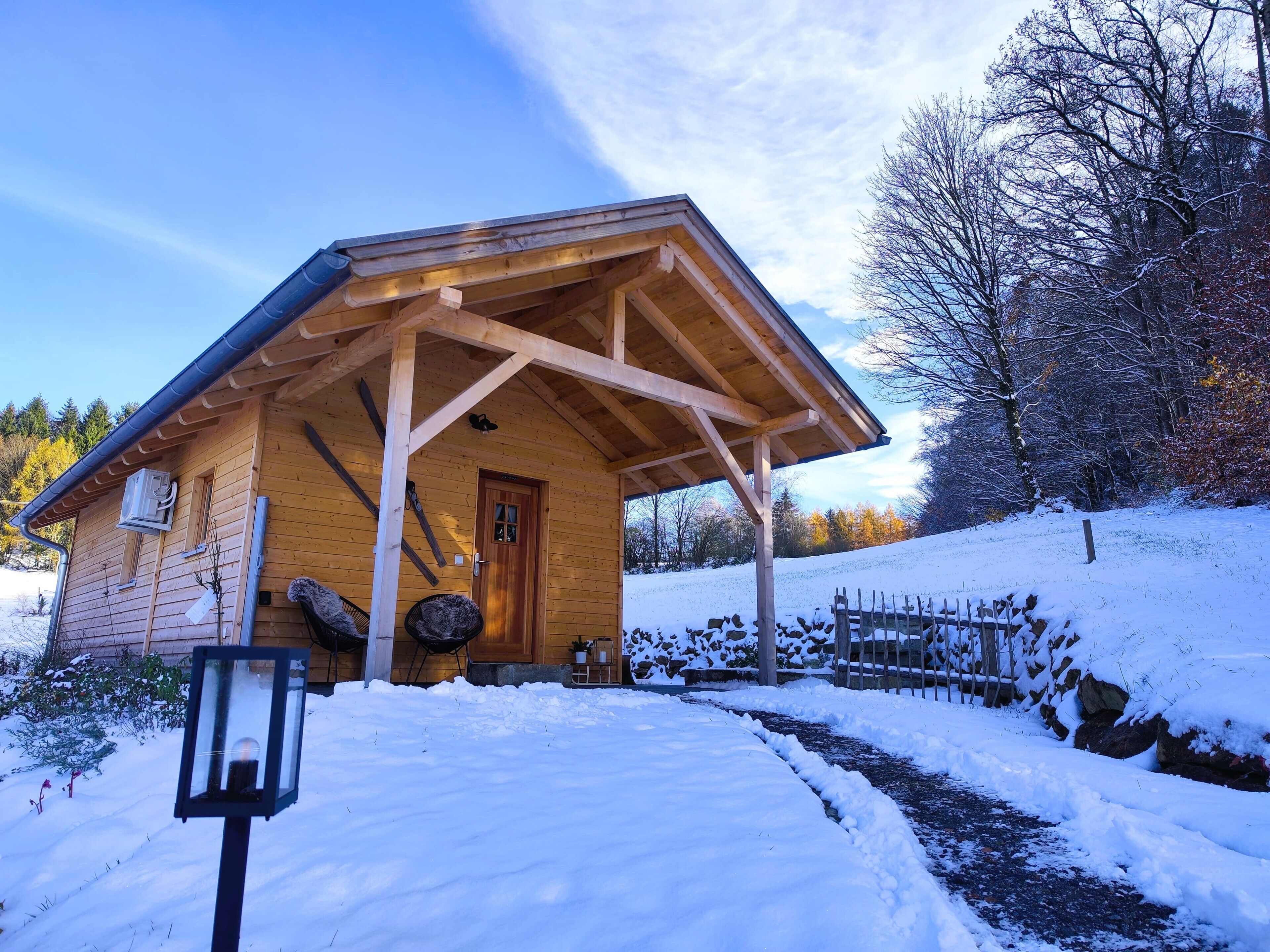 Une cabane en bois avec une véranda, une porte et une petite fenêtre.
