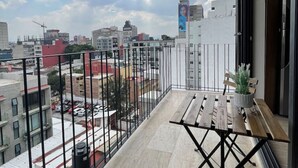 Un balcón con vista a la ciudad, una mesa y una planta en maceta.