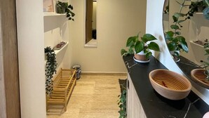 Un baño moderno con un espejo grande, estantes de madera y plantas en macetas.