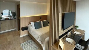 Una habitación de hotel moderna con cama, televisión, escritorio y zona de estar.