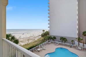 A balcony with a view of the beach, a swimming pool, and a building with balconies. - Marlin Key 2D (Orange Beach)