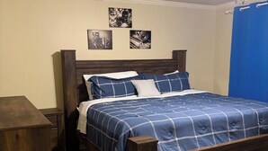 A bedroom with a wooden bed, a nightstand, a desk, and a ceiling fan. - Beautiful 4-bedroom house in tranquil Jackson perfect for families (Jackson)