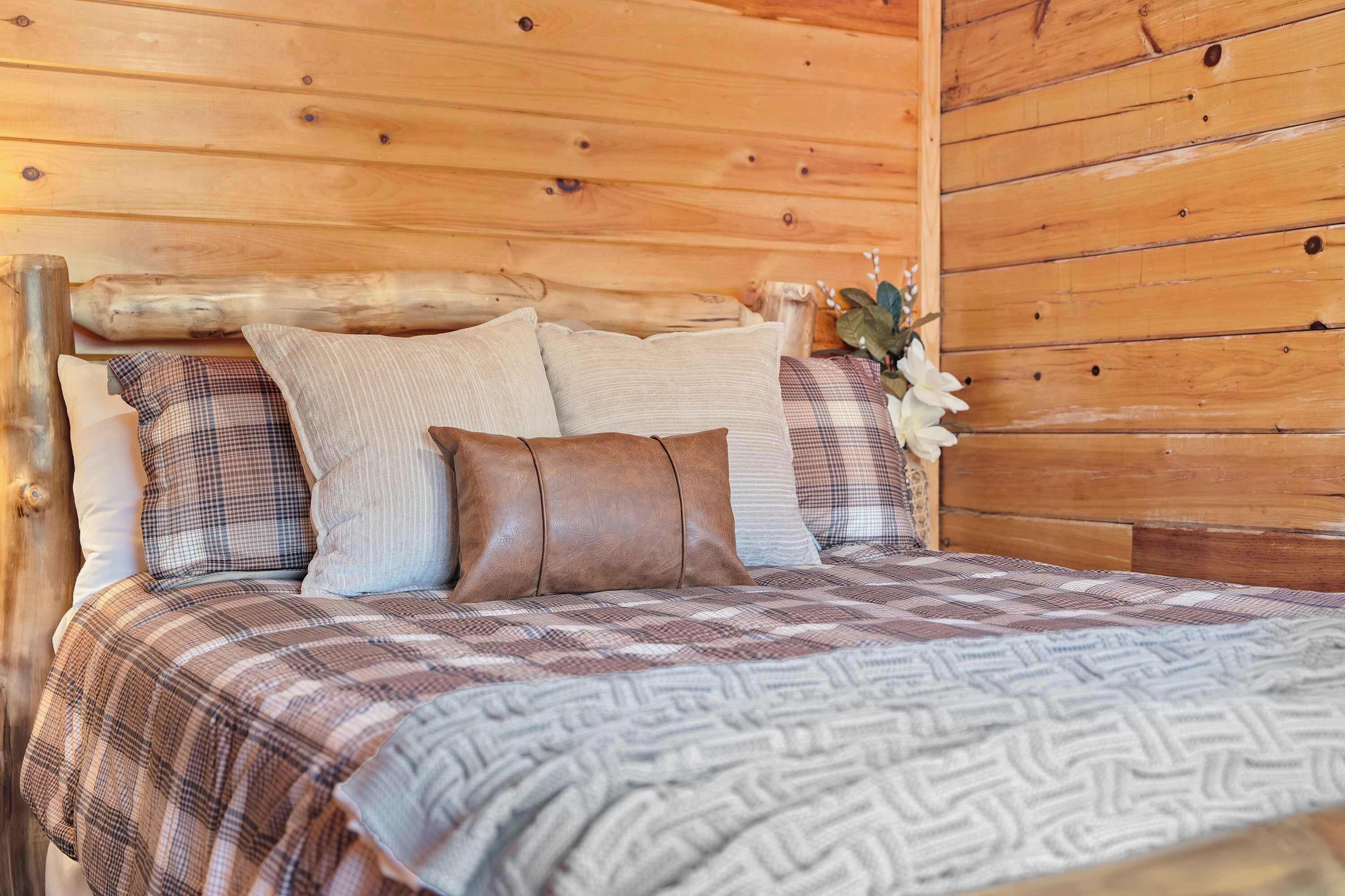 Ein Interieur einer Holzhütte mit einem Bett, Kissen und einer Zimmerpflanze.