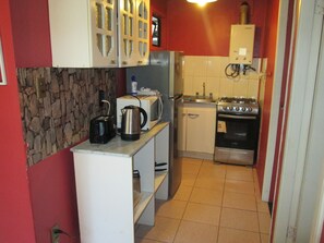 A compact kitchen with a refrigerator, stove, microwave, and a small countertop. - B1 Comfortable furnished 1-story apartment near downtown Puerto Montt (Puerto Montt)
