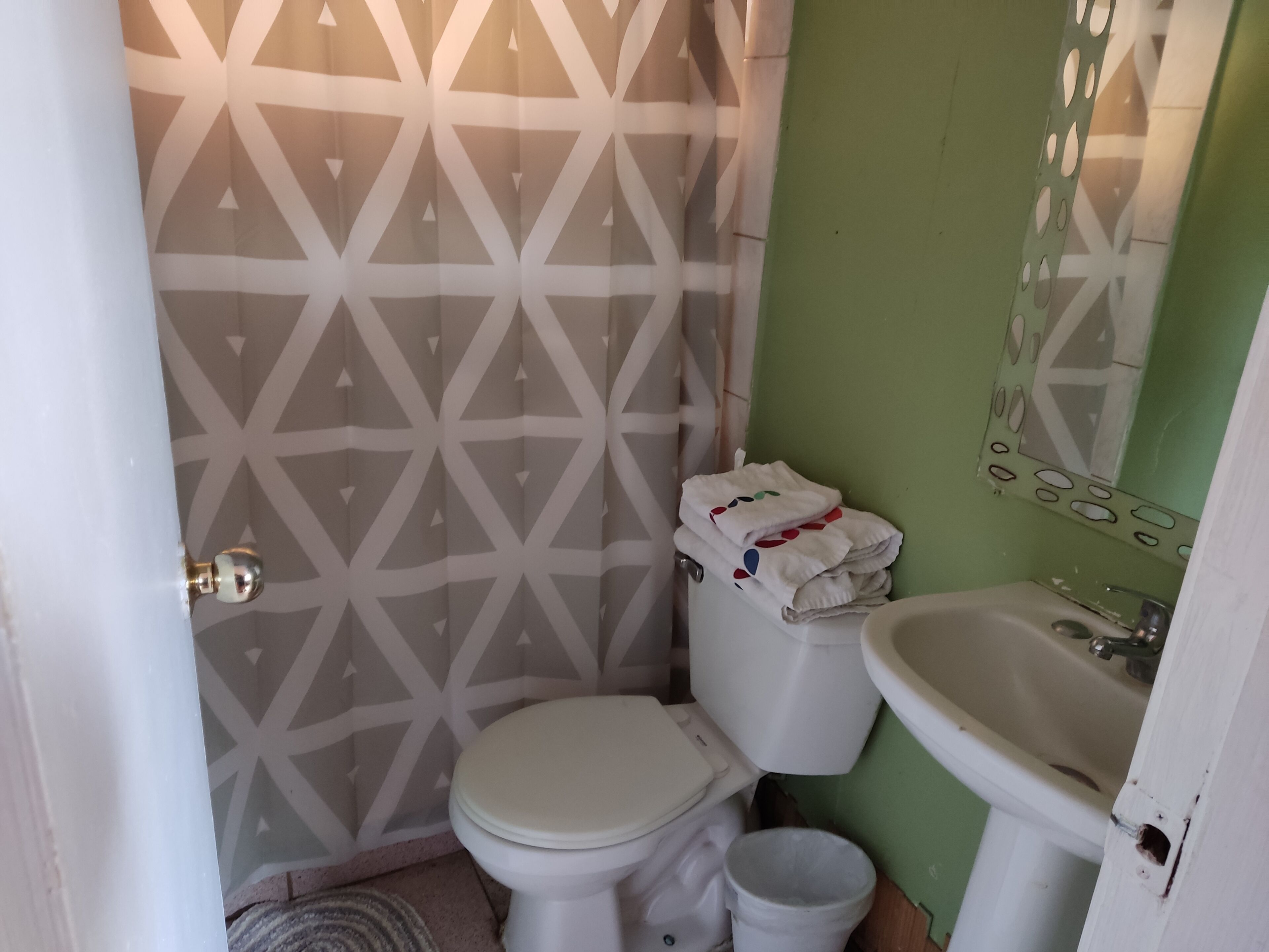 A small bathroom with a toilet, a sink, and a patterned wall.