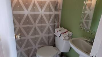 A small bathroom with a toilet, a sink, and a patterned wall.