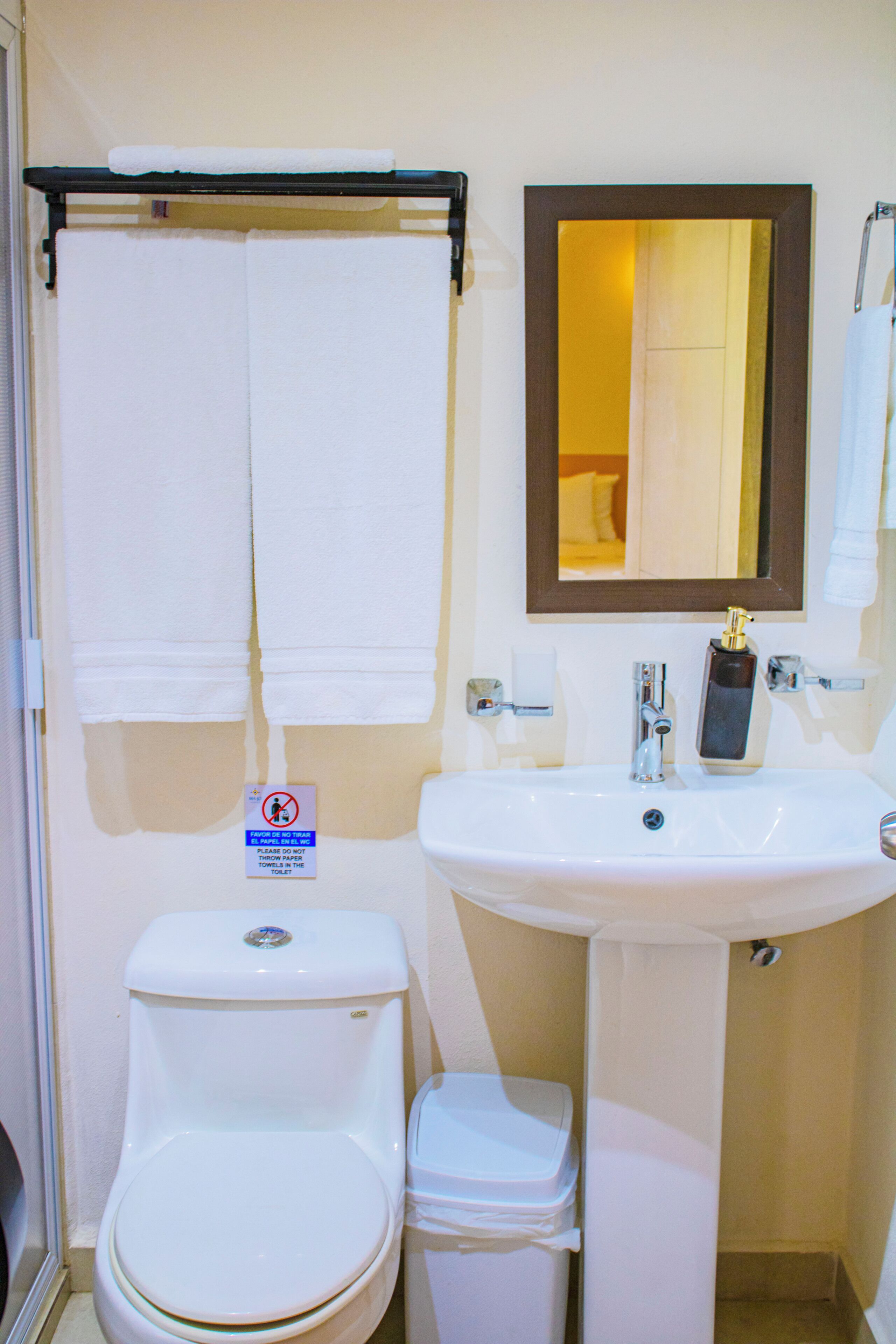 A bathroom with a toilet, sink, and a towel rack with two towels.