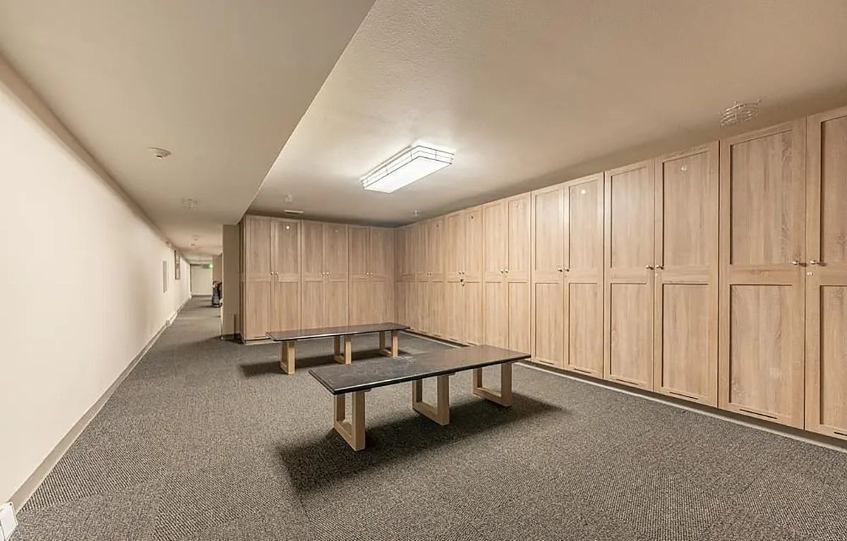 Un couloir avec une longue table, des meubles en bois et un sol recouvert de moquette.