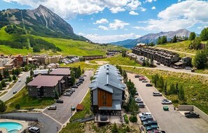 A resort with a pool, a mountain backdrop, and a parking lot. - Cozy Mountain Escape | Near Lifts + Trails (Mt. Crested Butte)