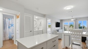 Una cocina moderna con armarios blancos, una isla grande y vistas al exterior.