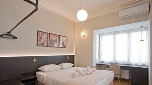 Une chambre d’hôtel moderne équipée d’un lit, d’une table de chevet, d’œuvres d’art accrochées au mur et d’un bureau avec une chaise.