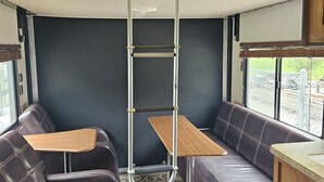 Ein kompaktes Wohnmobil-Interieur mit einer Sitzecke, einem kleinen Tisch, einer Treppe und einem Schrank.