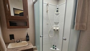 Ein Badezimmer mit einer Duschkabine, einem Waschbecken mit Spiegel darüber und einer Toilette.