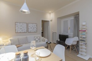 A modern living room with a sofa, dining table, and chairs. There is a TV, a fireplace, and a bookshelf. - One-bedroom apartment on the first floor in the heart of Brera, Milan’s artistic and bohemian district. A strategic location just steps from the Pinacoteca di Brera, La Scala Theatre, and Castello Sforzesco.An elegant apartment offering all modern comf (Milan)