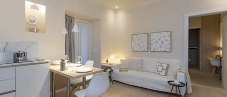 A modern living room with a sofa, a dining table, and a kitchen area.