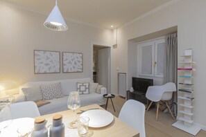 A modern living room with a sofa, dining table, and chairs. There is a TV, a fireplace, and a bookshelf. - One-bedroom apartment on the first floor in the heart of Brera, Milan’s artistic and bohemian district. A strategic location just steps from the Pinacoteca di Brera, La Scala Theatre, and Castello Sforzesco.An elegant apartment offering all modern comf (Milan)