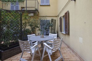 A courtyard with a round table and white chairs, surrounded by a low fence and potted plants. - One-bedroom apartment on the first floor in the heart of Brera, Milan’s artistic and bohemian district. A strategic location just steps from the Pinacoteca di Brera, La Scala Theatre, and Castello Sforzesco.An elegant apartment offering all modern comf (Milan)